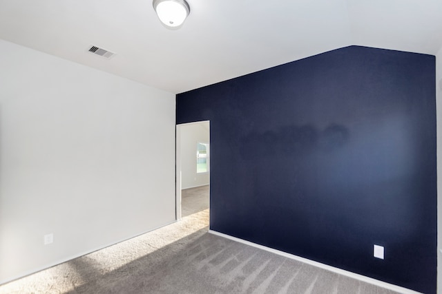 carpeted empty room with lofted ceiling