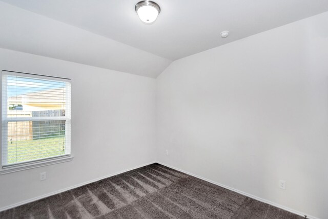 carpeted spare room with vaulted ceiling