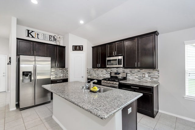 kitchen featuring stainless steel appliances, sink, backsplash, an island with sink, and vaulted ceiling