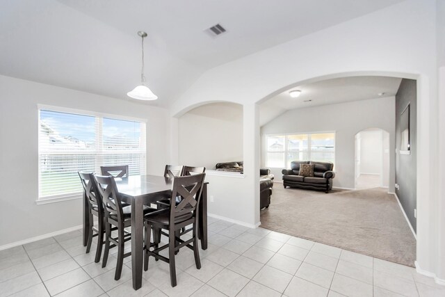 carpeted dining area with lofted ceiling and a healthy amount of sunlight