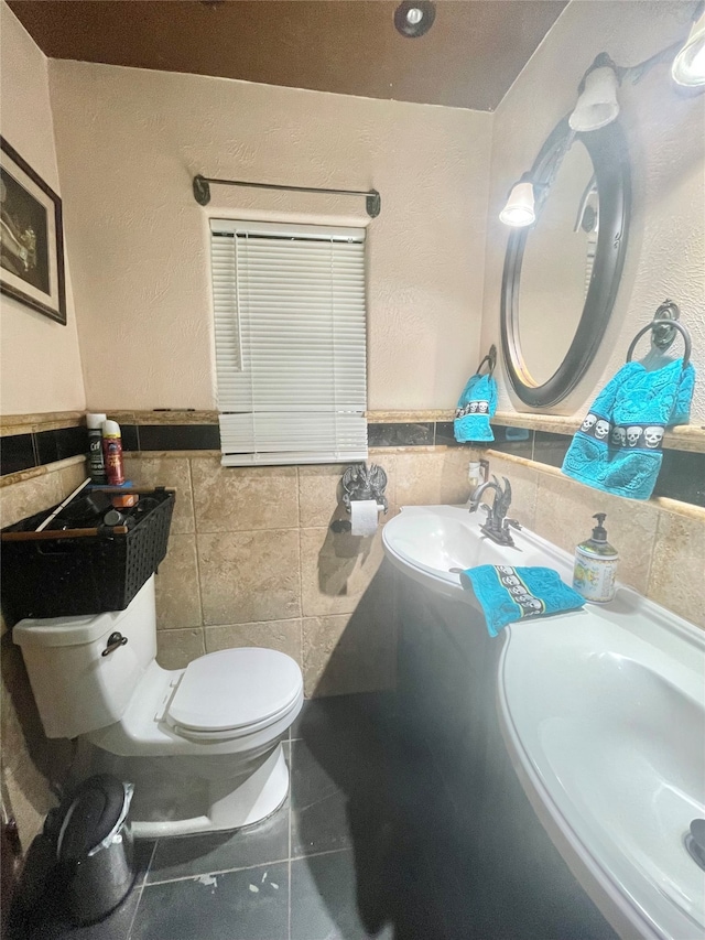 bathroom with toilet, tile walls, sink, and tile patterned floors