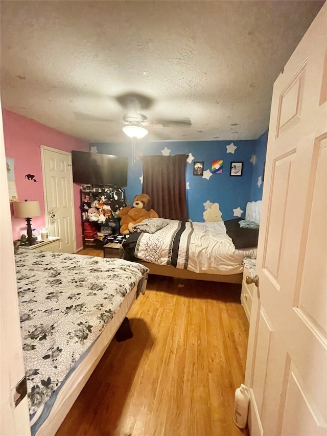 bedroom featuring light hardwood / wood-style floors, a textured ceiling, and ceiling fan