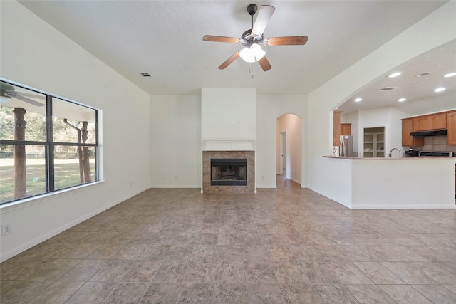 unfurnished living room featuring a tile fireplace and ceiling fan