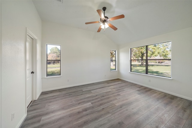 spare room featuring lofted ceiling, a healthy amount of sunlight, light hardwood / wood-style floors, and ceiling fan