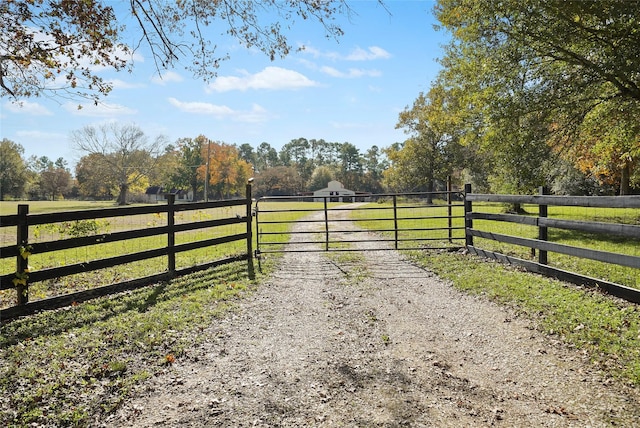 view of gate featuring a rural view, a yard, and fence