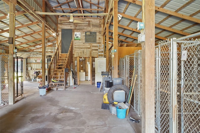 miscellaneous room with concrete floors, high vaulted ceiling, and wooden walls