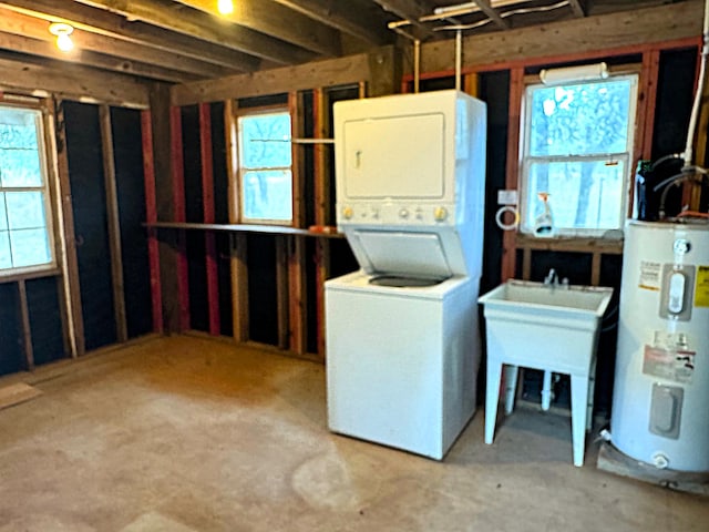 basement with water heater, a healthy amount of sunlight, and stacked washer / drying machine