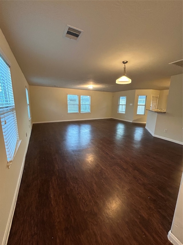 unfurnished living room featuring a wealth of natural light and dark hardwood / wood-style flooring