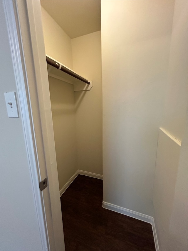 walk in closet with dark wood-type flooring