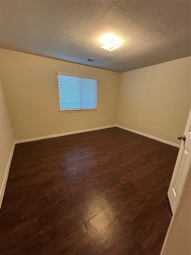 unfurnished room featuring dark hardwood / wood-style flooring and a textured ceiling