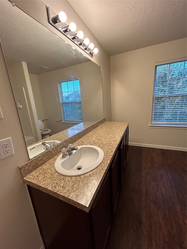 bathroom with wood-type flooring, vanity, toilet, and a textured ceiling