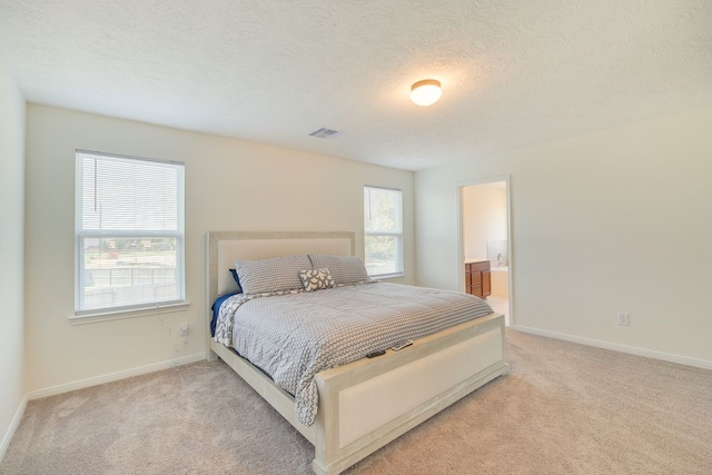 carpeted bedroom featuring ensuite bath and a textured ceiling