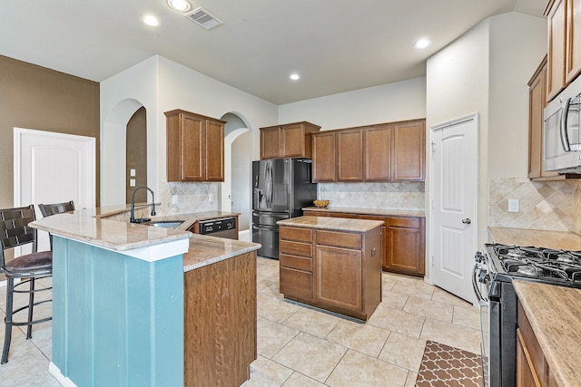 kitchen featuring stainless steel appliances, sink, kitchen peninsula, light stone countertops, and a center island