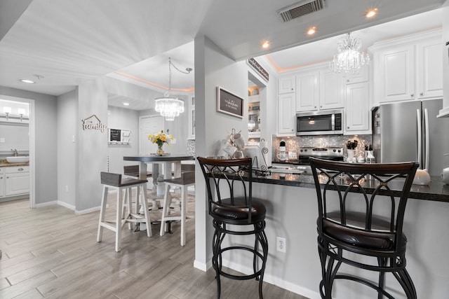 kitchen featuring a kitchen bar, white cabinetry, light hardwood / wood-style flooring, and appliances with stainless steel finishes