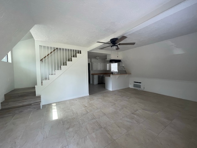 unfurnished living room with a wall unit AC, a textured ceiling, ceiling fan, and vaulted ceiling