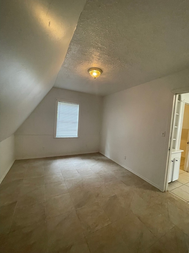 additional living space featuring a textured ceiling and vaulted ceiling