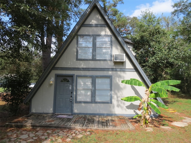 english style home with an AC wall unit and a deck