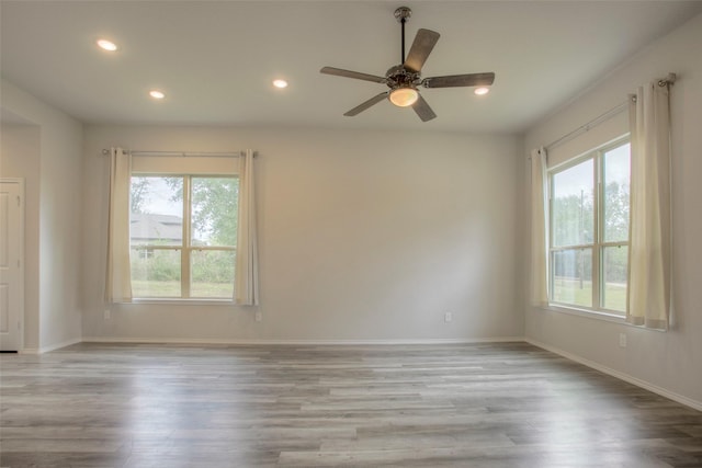 spare room featuring ceiling fan, light hardwood / wood-style flooring, and a healthy amount of sunlight