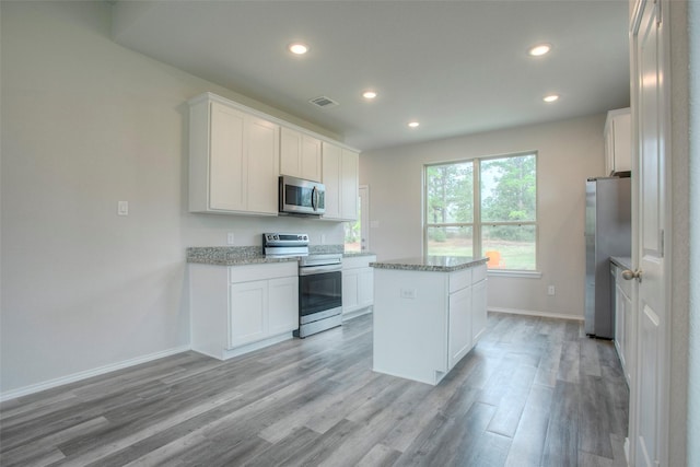 kitchen featuring white cabinets, a center island, stainless steel appliances, and light hardwood / wood-style floors