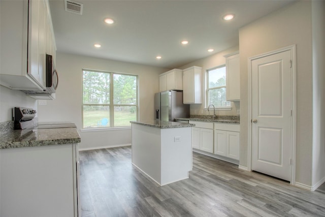 kitchen with plenty of natural light, a kitchen island, stove, and white cabinetry