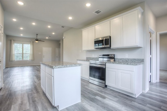 kitchen with white cabinets, light hardwood / wood-style flooring, ceiling fan, appliances with stainless steel finishes, and a kitchen island