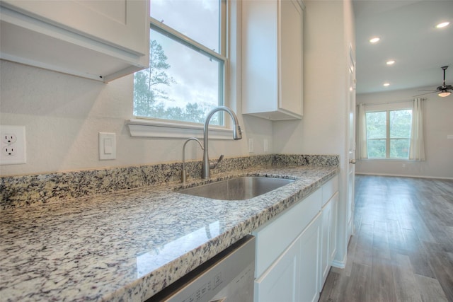 kitchen with white cabinetry, light stone countertops, wood-type flooring, and sink