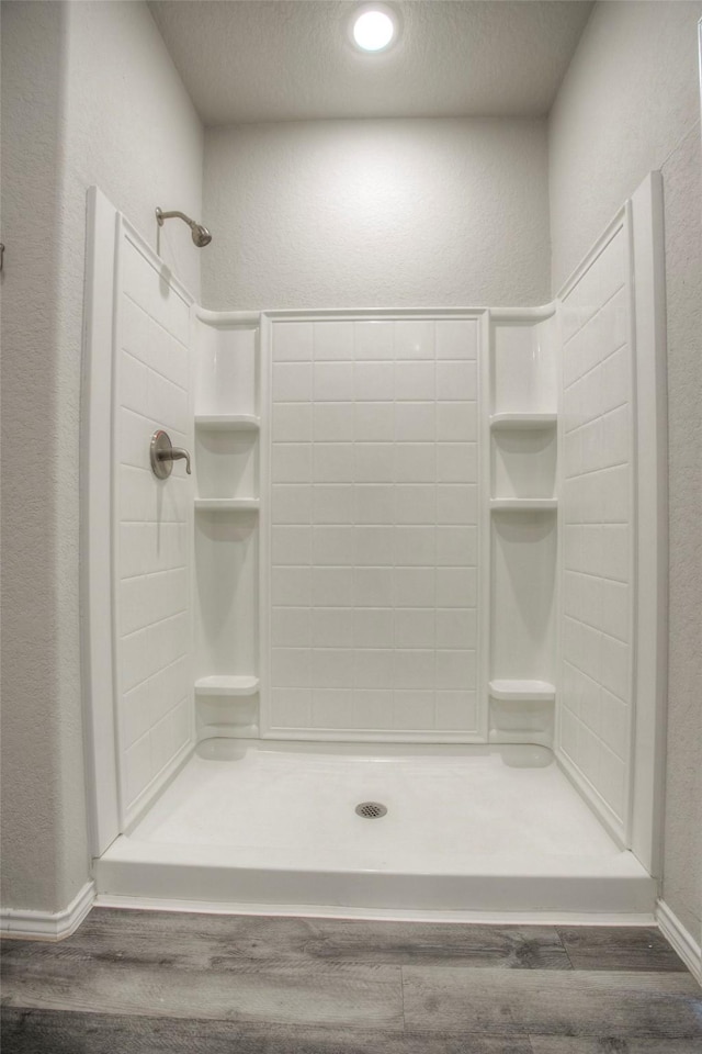 bathroom with a shower, wood-type flooring, and a textured ceiling