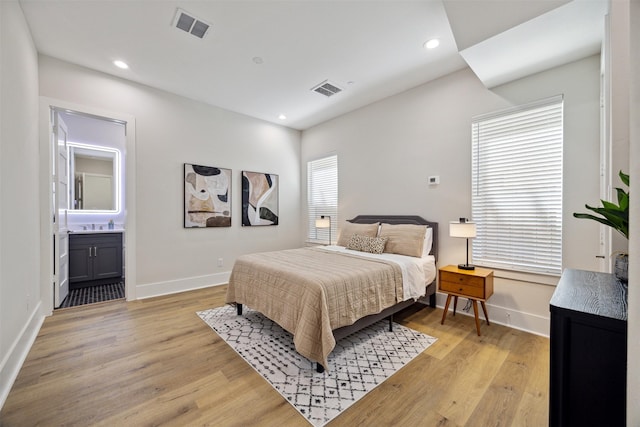 bedroom featuring connected bathroom and light wood-type flooring