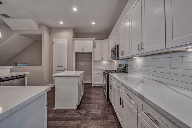 kitchen with white cabinetry, stainless steel appliances, dark hardwood / wood-style floors, and light stone countertops