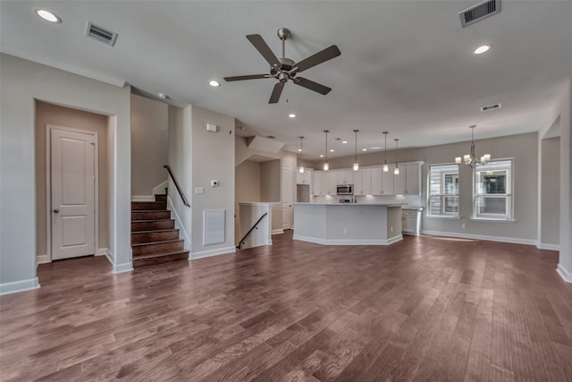 unfurnished living room featuring dark wood-type flooring and ceiling fan with notable chandelier