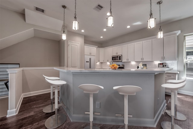 kitchen featuring white cabinetry, dark hardwood / wood-style floors, hanging light fixtures, a spacious island, and decorative backsplash