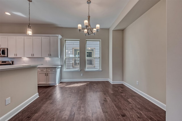 kitchen with tasteful backsplash, stainless steel appliances, white cabinetry, dark hardwood / wood-style flooring, and hanging light fixtures