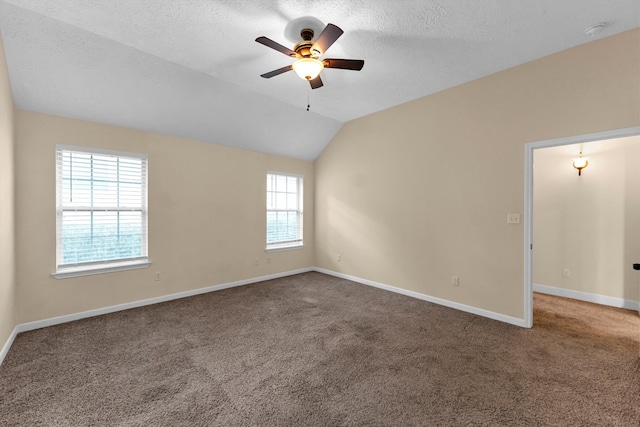 empty room featuring ceiling fan, a textured ceiling, lofted ceiling, and carpet