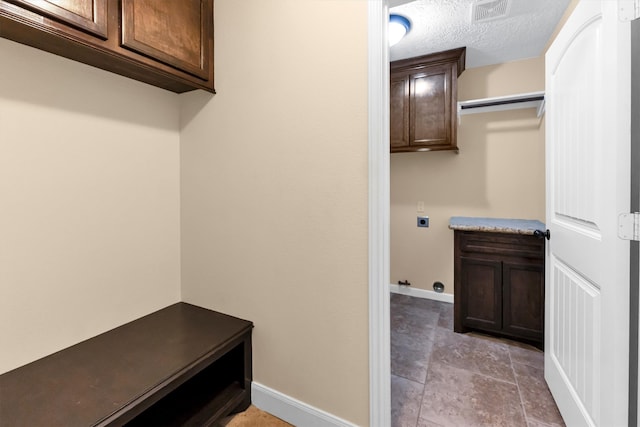 interior space with cabinets, a textured ceiling, and hookup for an electric dryer