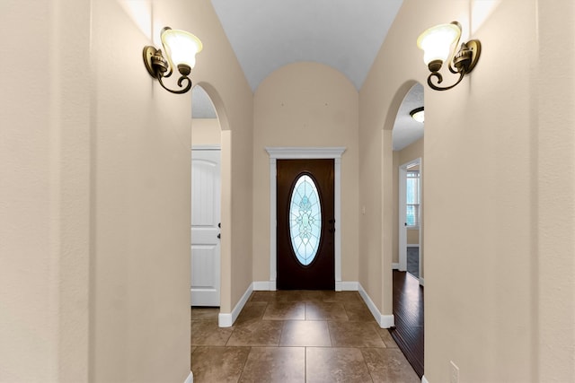 entrance foyer featuring dark tile patterned flooring and vaulted ceiling