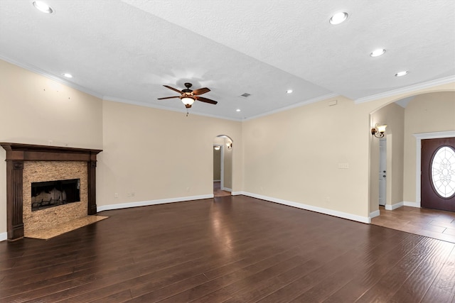 unfurnished living room featuring dark wood-type flooring, ceiling fan, a textured ceiling, and crown molding