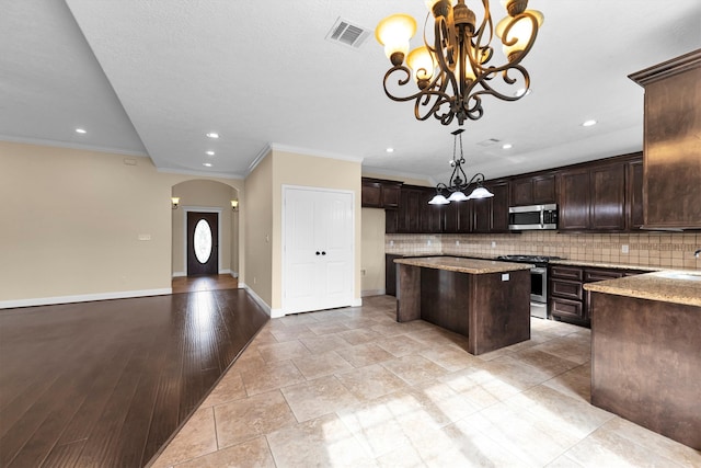 kitchen featuring dark brown cabinets, light stone countertops, pendant lighting, light wood-type flooring, and appliances with stainless steel finishes