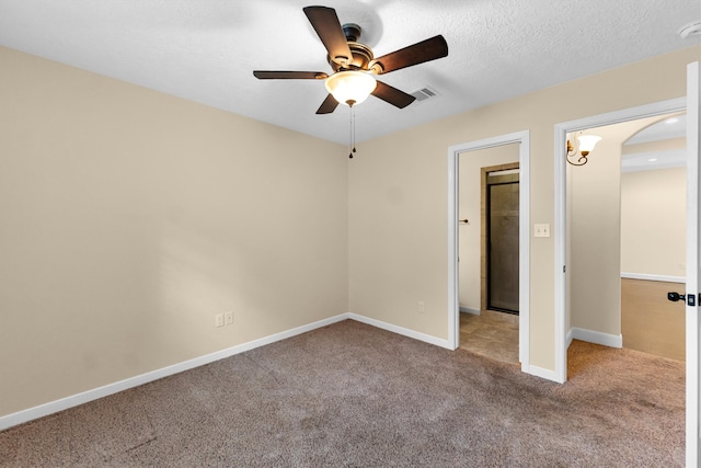 unfurnished bedroom with a textured ceiling, light colored carpet, and ceiling fan