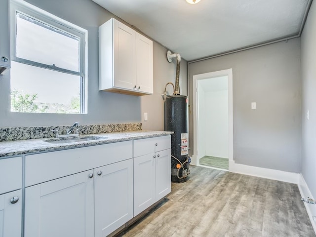 kitchen featuring gas water heater, white cabinetry, sink, and light wood-type flooring