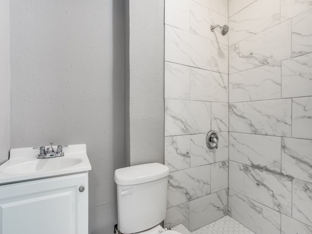 bathroom featuring toilet, vanity, and a tile shower