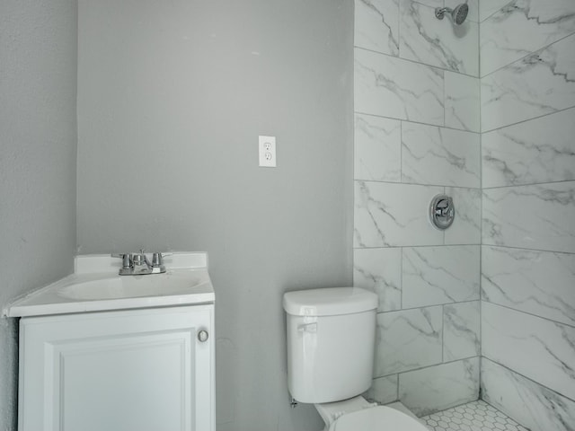 bathroom with toilet, vanity, and tiled shower