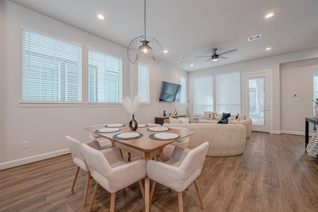 dining area featuring a wealth of natural light, wood-type flooring, and ceiling fan with notable chandelier