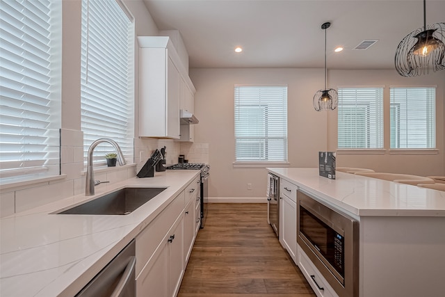 kitchen with hanging light fixtures, sink, and white cabinets