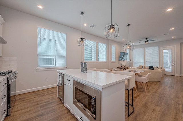 kitchen with stainless steel appliances, white cabinetry, plenty of natural light, and light hardwood / wood-style flooring