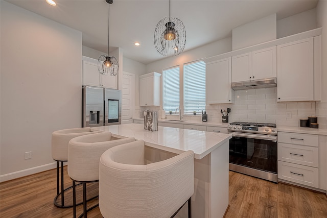 kitchen featuring a center island, appliances with stainless steel finishes, hanging light fixtures, white cabinets, and light hardwood / wood-style flooring