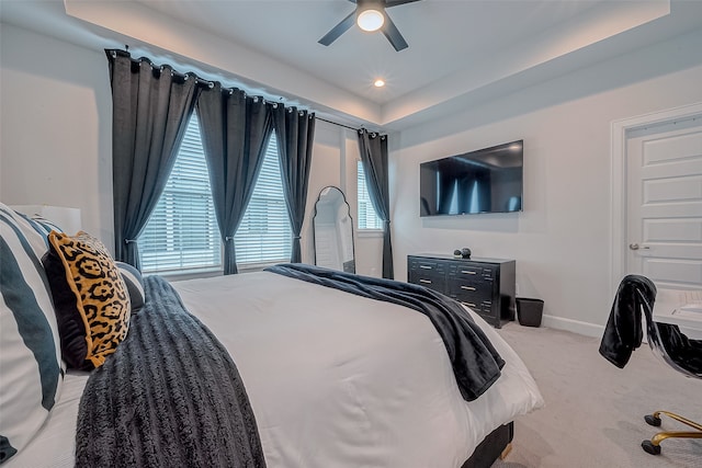 carpeted bedroom featuring ceiling fan and a raised ceiling