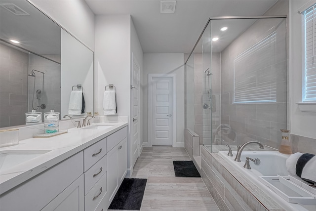 bathroom with a healthy amount of sunlight, vanity, hardwood / wood-style flooring, and independent shower and bath