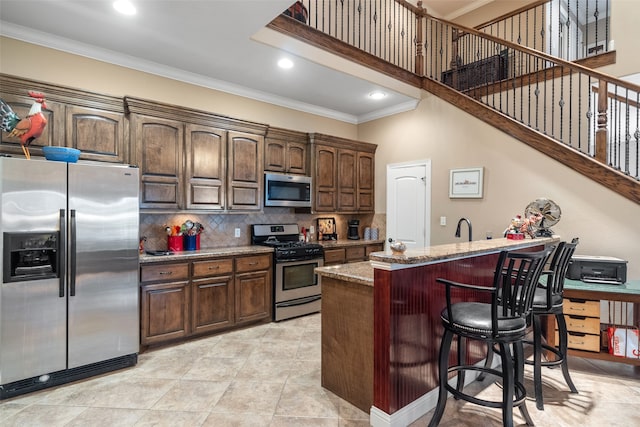 kitchen featuring sink, stainless steel appliances, a kitchen breakfast bar, light stone counters, and an island with sink