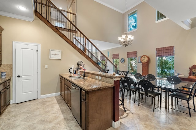 kitchen featuring dishwasher, a towering ceiling, decorative light fixtures, and sink