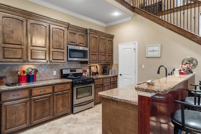 kitchen featuring a kitchen island with sink, a breakfast bar, stainless steel appliances, and light stone counters